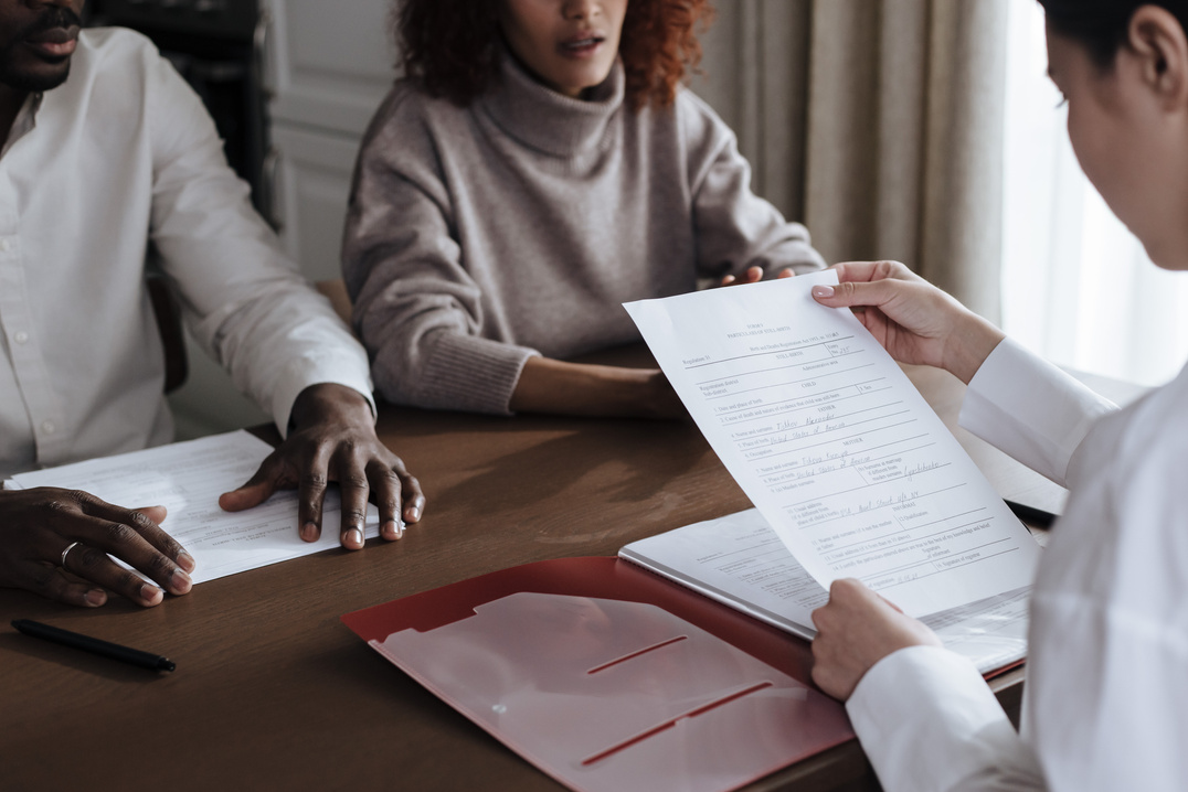 Unrecognizable Afro-American Man and Caucasian Woman Talking with Female Social Worker